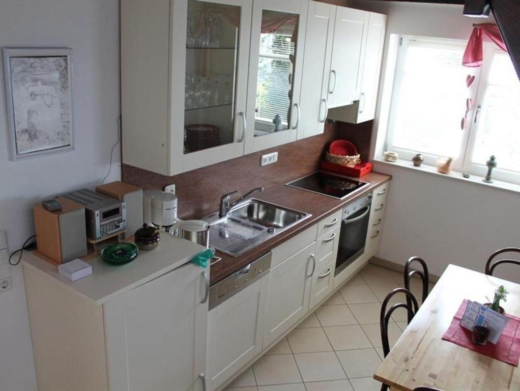 eine Küche mit weißen Schränken, einer Spüle und einem Tisch in der Unterkunft Ferienhaus 258 S in Eckwarden in Eckwarden