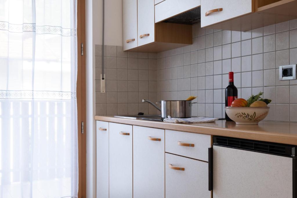 una cocina con armarios blancos y fregadero en Ferienwohnung im Haus Texel V, en Rablà