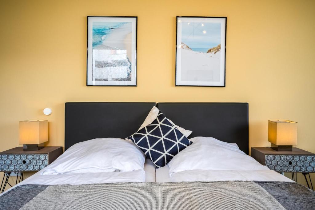 een slaapkamer met een bed met drie foto's aan de muur bij Studio 16 "Sandmeer" mit Meerblick in Grömitz