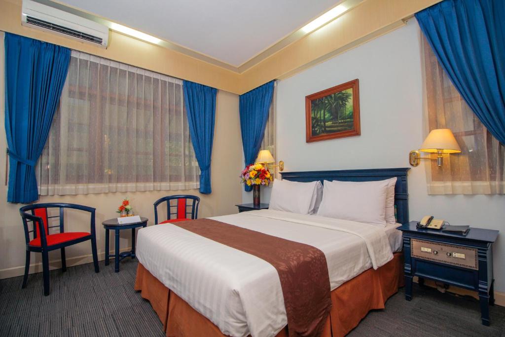 a hotel room with a large bed and blue curtains at Sapta Nawa Resort 1 Gresik in Gresik
