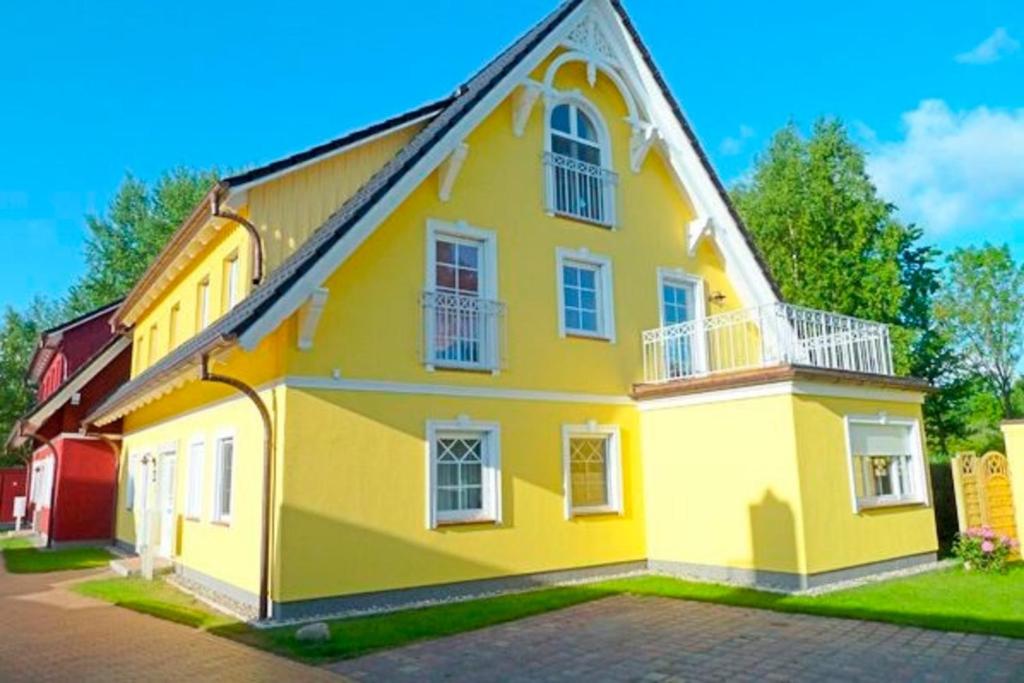 uma casa amarela com janelas brancas numa rua em Villa Arielle, FW 8 em Zingst