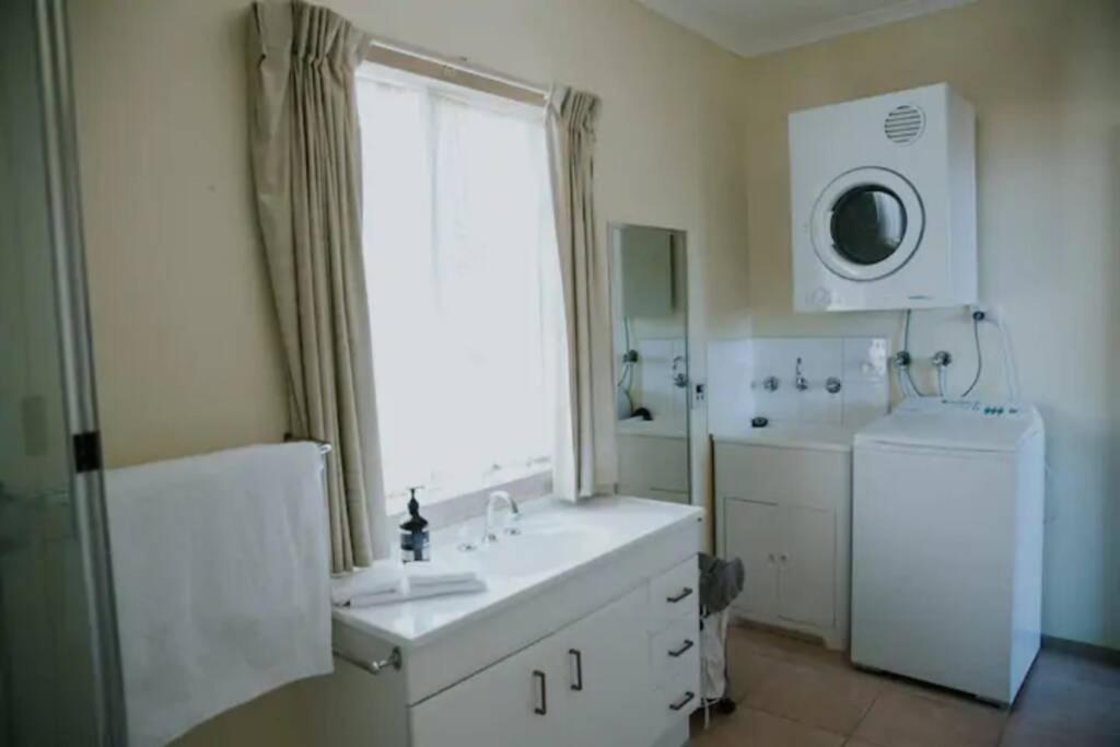 a white bathroom with a sink and a window at The Shack at Skenes Creek in Apollo Bay