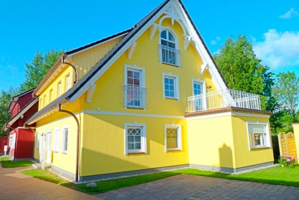 a yellow house with white windows on a street at Villa Arielle, FW 4 in Zingst