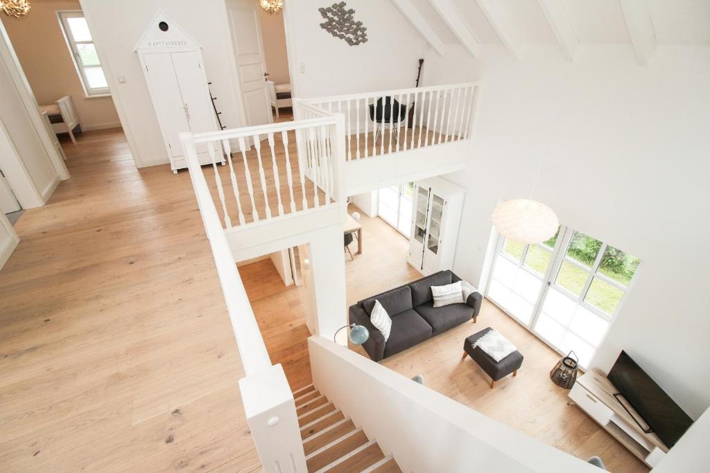 einen Blick über ein Wohnzimmer mit Sofa und Treppe in der Unterkunft DeichGalerie89 - a48723 in Krummhörn