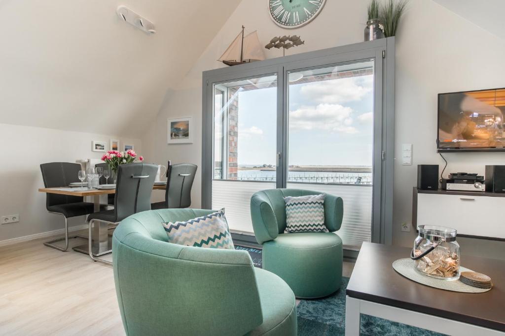 ハイリゲンハーフェンにあるOstsee - Appartement Nr 30 ''Küstenkieker'' im Strand Resortのリビングルーム(椅子、テーブル付)、窓が備わります。