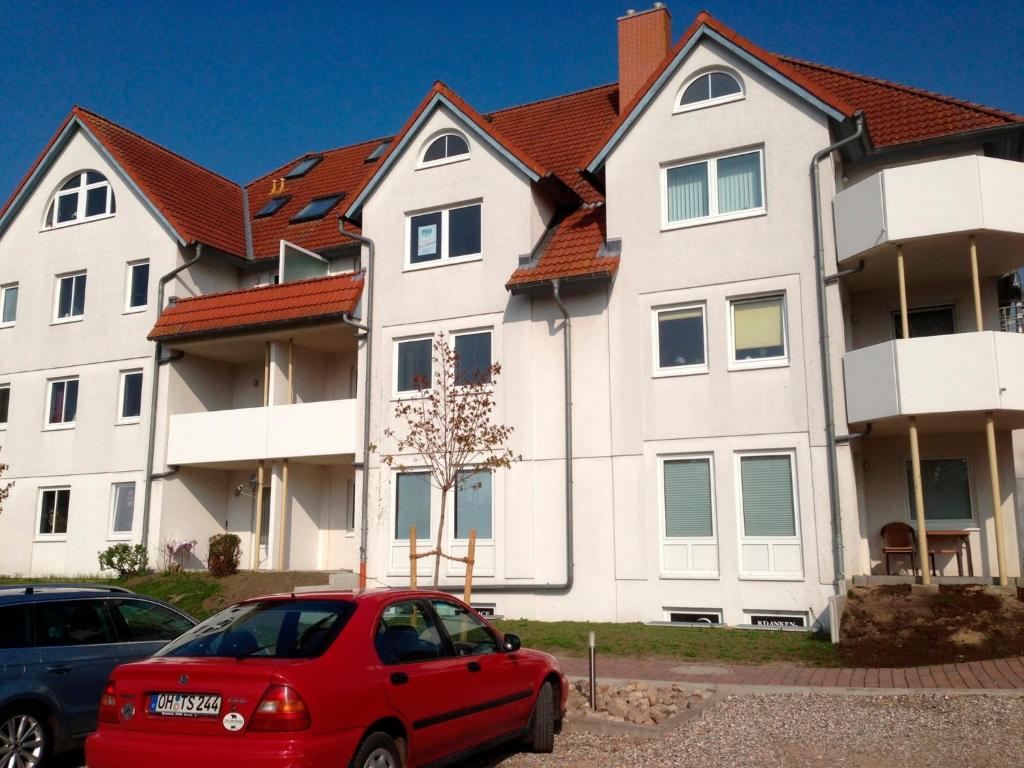 a red car parked in front of a large building at Ferienwohnung Ertl - 14518 in Petersdorf auf Fehmarn