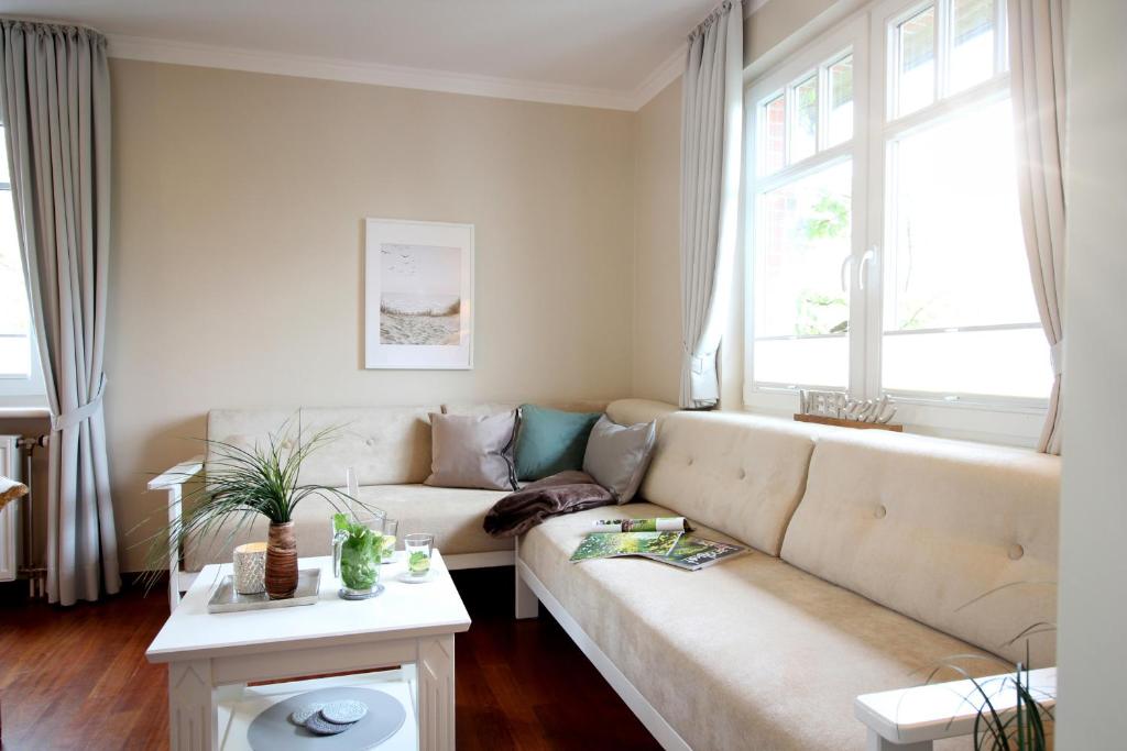 sala de estar con sofá y 2 ventanas en Haus am Park Wohnung Nr10, en Spiekeroog