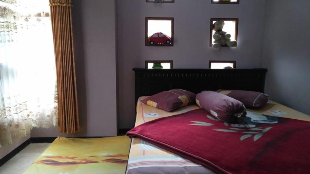 a bedroom with a bed with purple pillows on it at Villa Trijaya in Batu