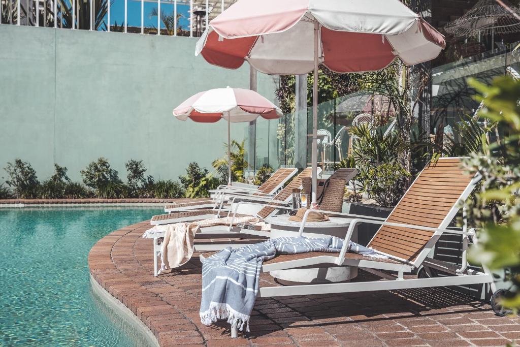 una fila de sillas y sombrillas junto a una piscina en The Island Gold Coast en Gold Coast