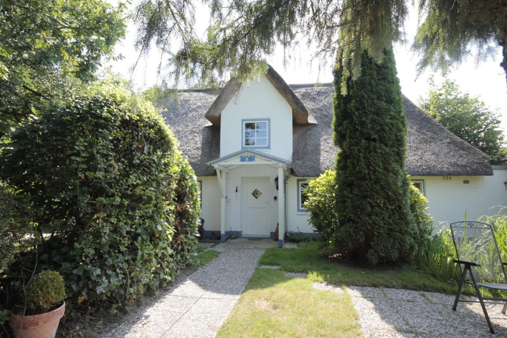 ein Haus mit einer weißen Tür und einem Baum in der Unterkunft Hus Boompecker in Achtrup