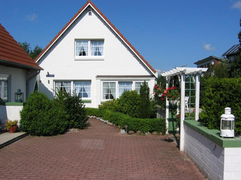 ein weißes Haus mit einer steinernen Einfahrt in der Unterkunft Am Maisfeld Ferienhaus in Wyk auf Föhr