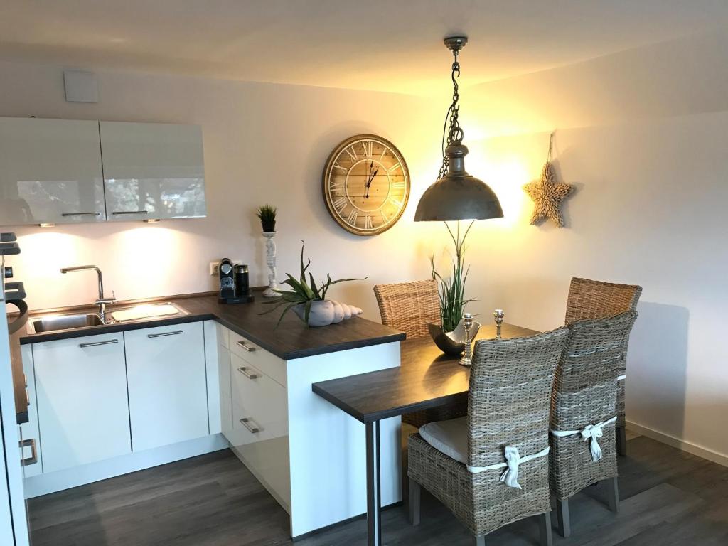 a kitchen with a table and chairs and a clock on the wall at "Strandvilla Seagull - Whg Sunset" in Grömitz