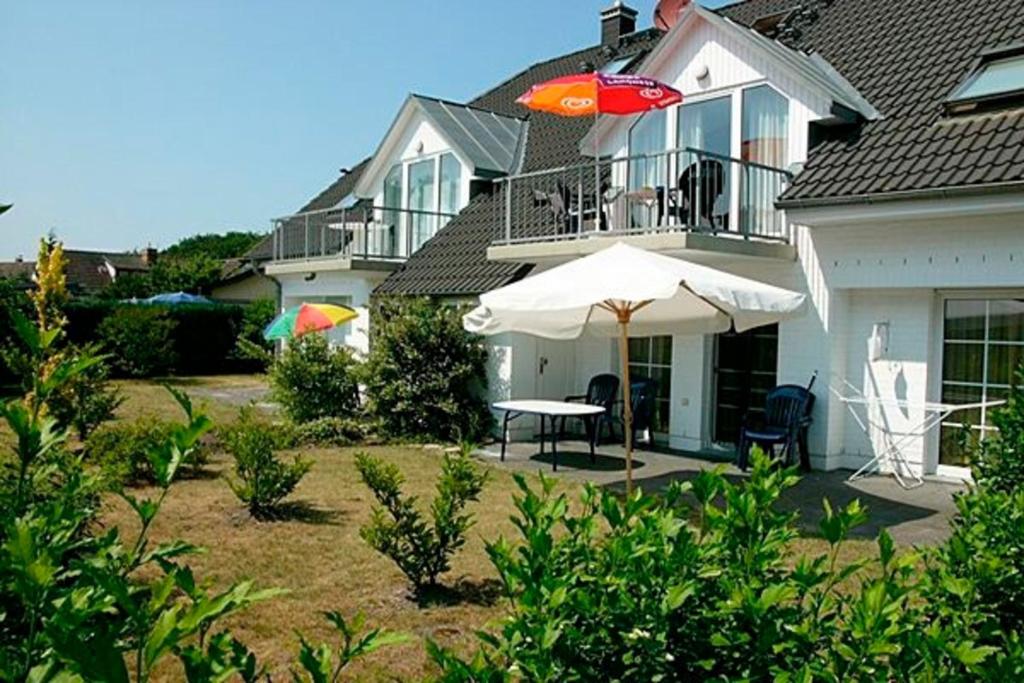 a house with an umbrella and a table and chairs at Seeblick 8, PP außen in Zingst