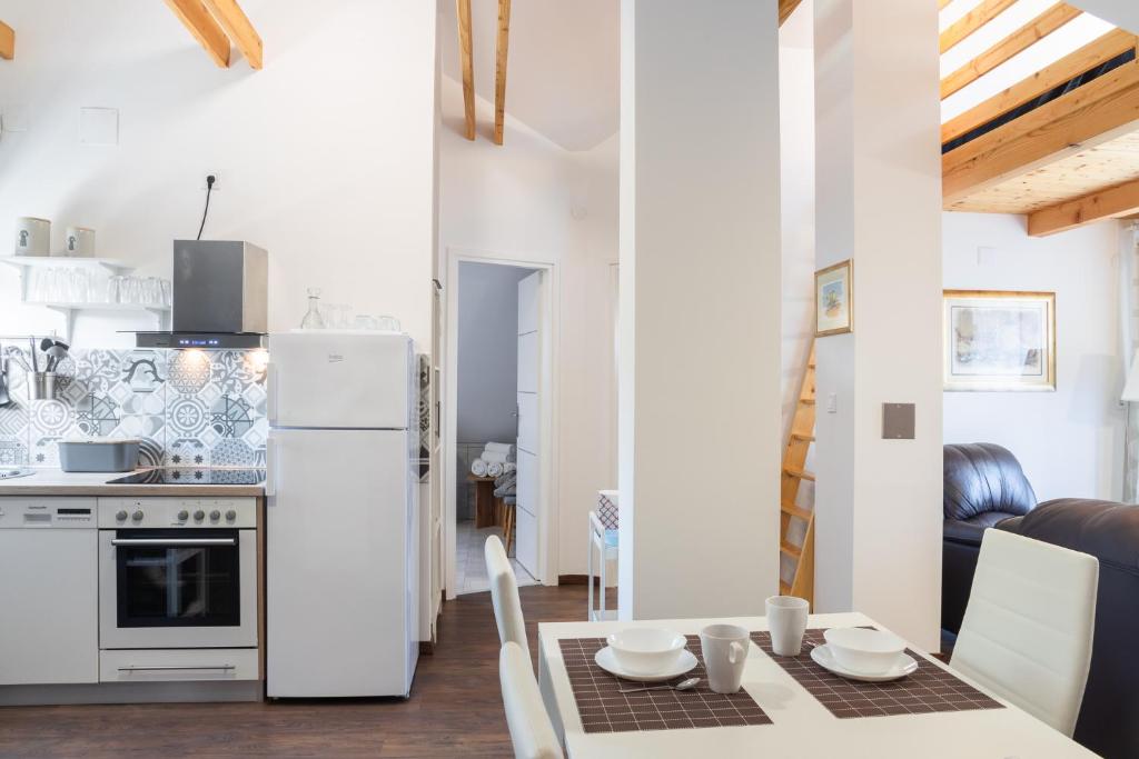 a kitchen with a table and a white refrigerator at Apartmani Vesna Tuheljske toplice in Tuheljske Toplice