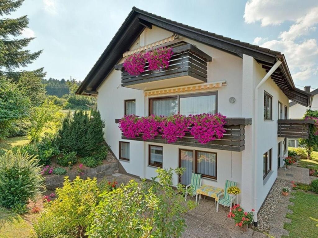 uma casa com flores cor-de-rosa numa varanda em 4-Sterne Wohnung im Erdgeschoss em Frutenhof