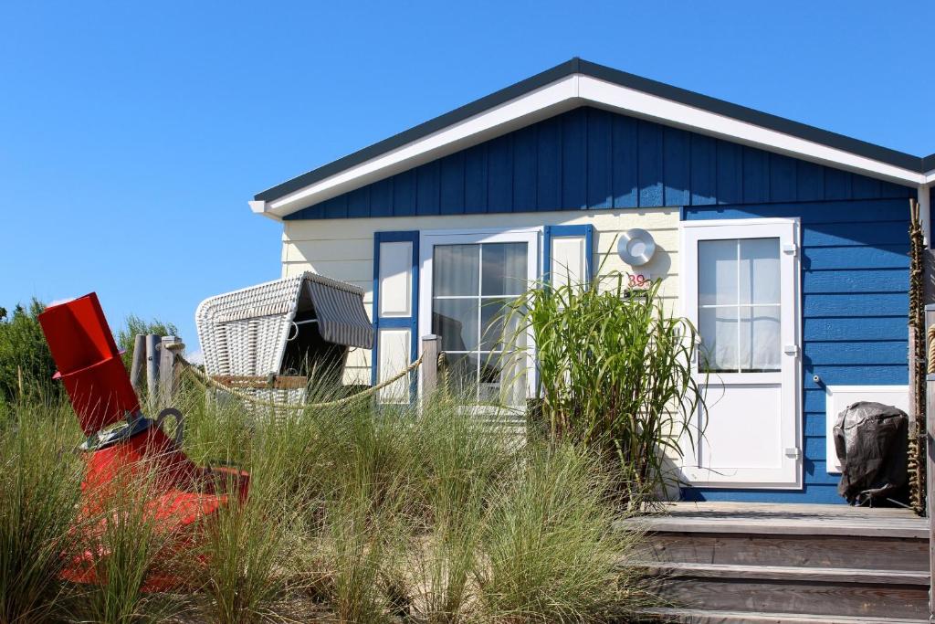 ein blaues Haus mit einer weißen Tür im Gras in der Unterkunft Welle 34a in Scharbeutz
