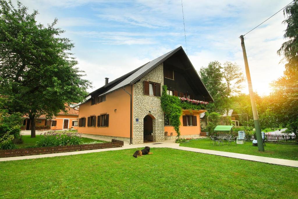 a dog laying on the grass in front of a house at Plitvice Rooms Family Glumac in Plitvička Jezera