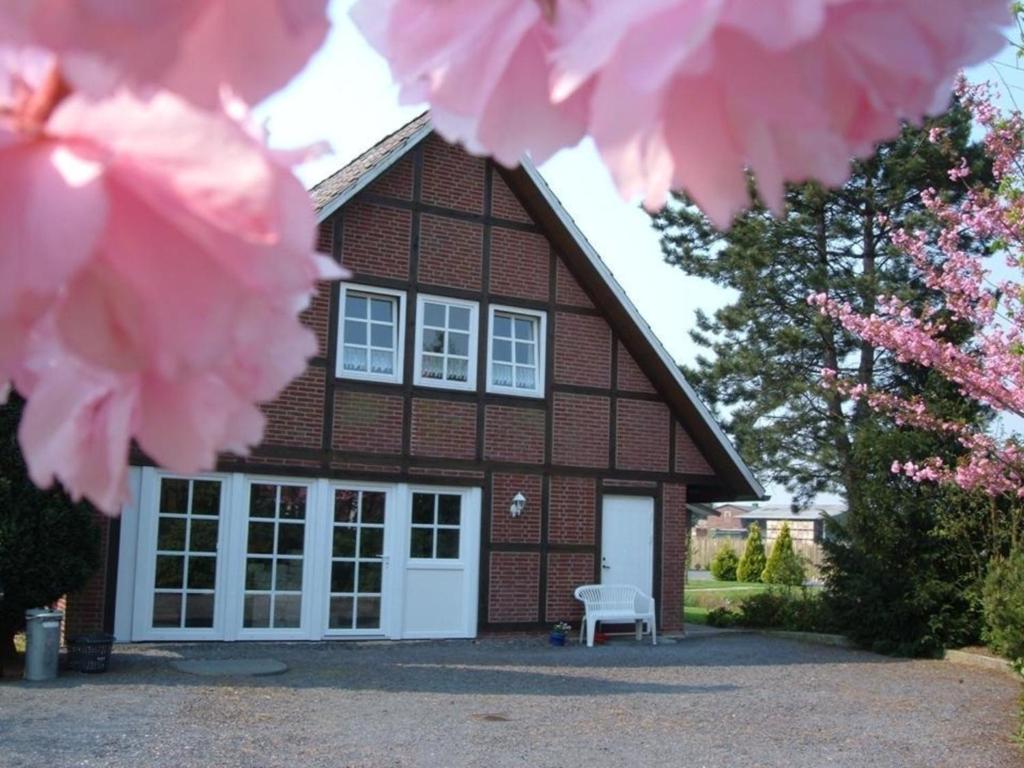 una casa de ladrillo con puertas blancas y flores rosas en Appartement Altes Land Jork bei HH en Jork