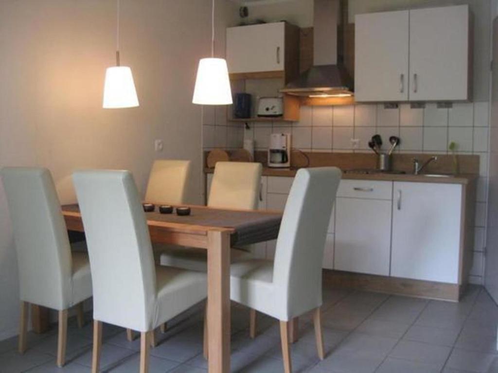a kitchen with a wooden table and white chairs at Ferienhaus 3370 in Tossens in Butjadingen OT Tossens