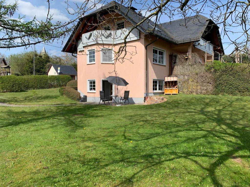 une grande maison rose avec une pelouse dans l'établissement Eifel Holiday, à Prüm
