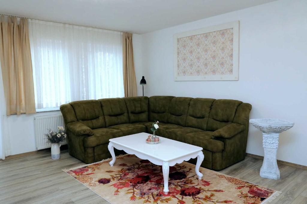 een woonkamer met een groene bank en een witte tafel bij Aparthotel Kompass A 201 in Essen