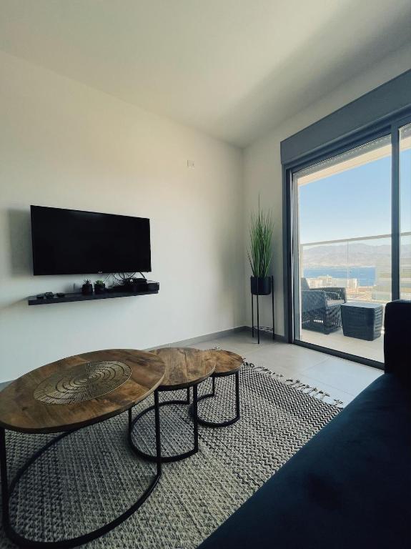 a living room with a table and a large window at דירת נופש ׳חושן׳ in Eilat