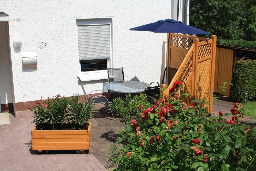 eine Terrasse mit einem Tisch, einem Sonnenschirm und Blumen in der Unterkunft Ferienhaus "Antonia" - a47030 in Witzenhausen