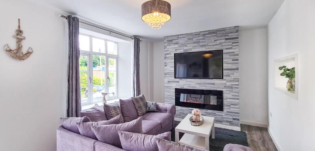 a living room with a purple couch and a fireplace at Driftwood Cottage, Luxury character cottage in The English Riviera, close to the picturesque precinct of St Marychurch, a short walk to the stunning beaches of Babbacombe and Oddicombe! in Torquay