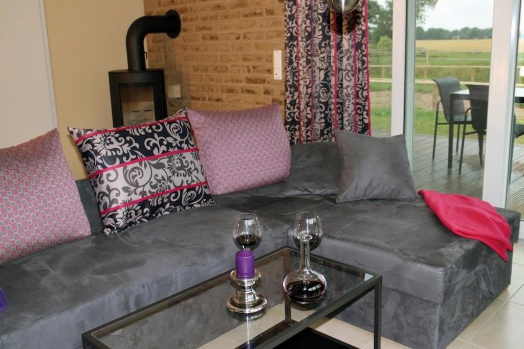 uma sala de estar com um sofá e dois copos de vinho em Kamaahr em Friedenstal