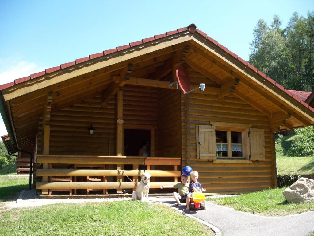 dos niños y un perro sentado frente a una cabaña de madera en Blockhaus Hedwig Haus 10, en Stamsried