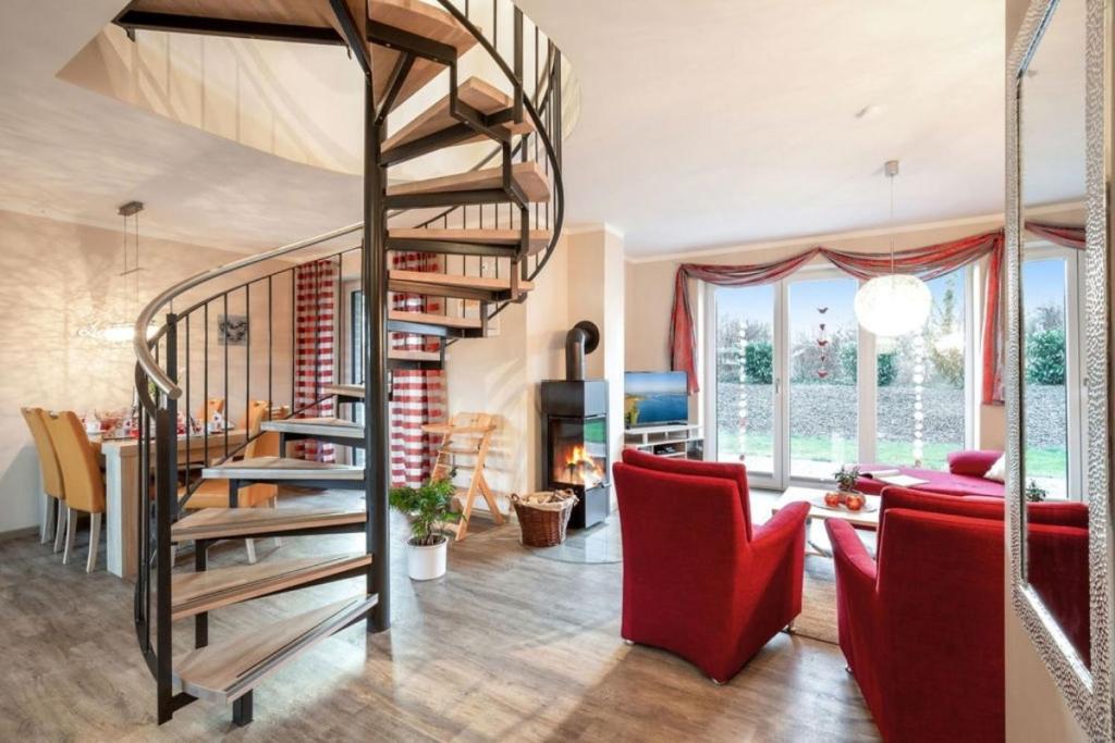 a living room with a spiral staircase and red chairs at Wellness - Ferienhaus Küstenwind in Klausdorf