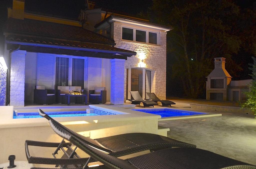 a swimming pool with chairs next to a house at night at Villa Bavaria Porec in Rošini