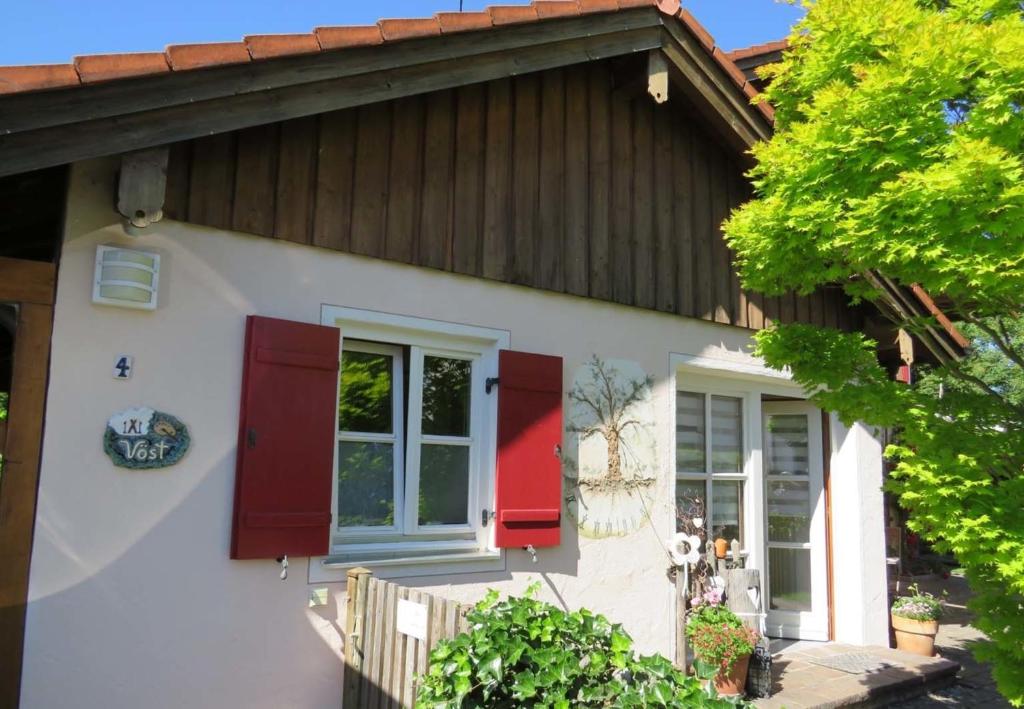 a white house with red shutters on it at Ferienwohnung Vöst in Peiting