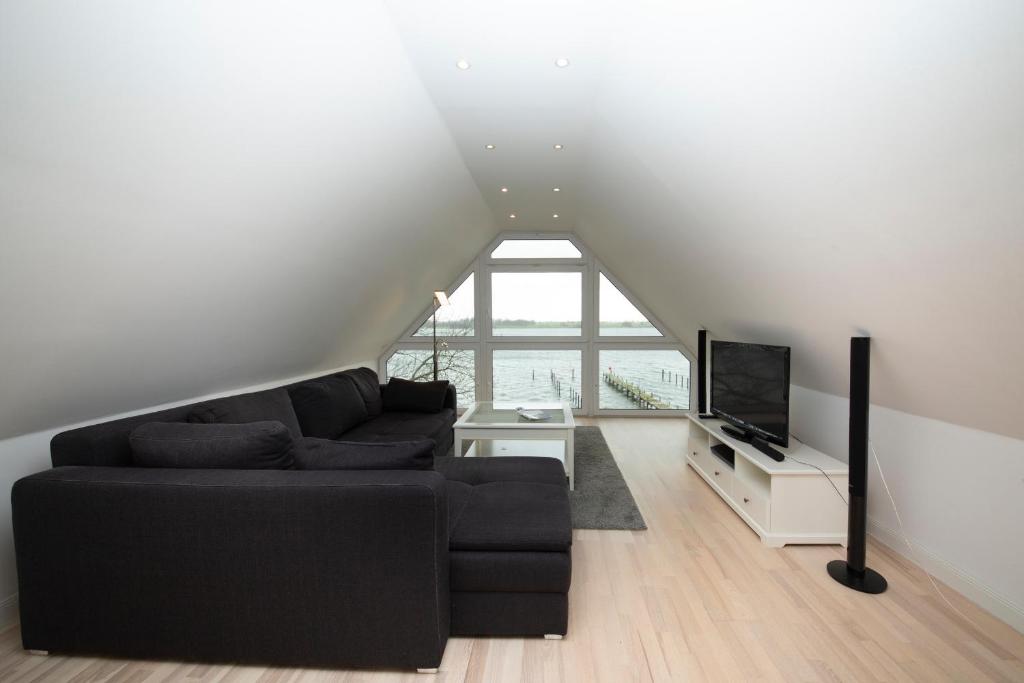 a living room with a black couch and a tv at Schleitraum Appartement in Karschau