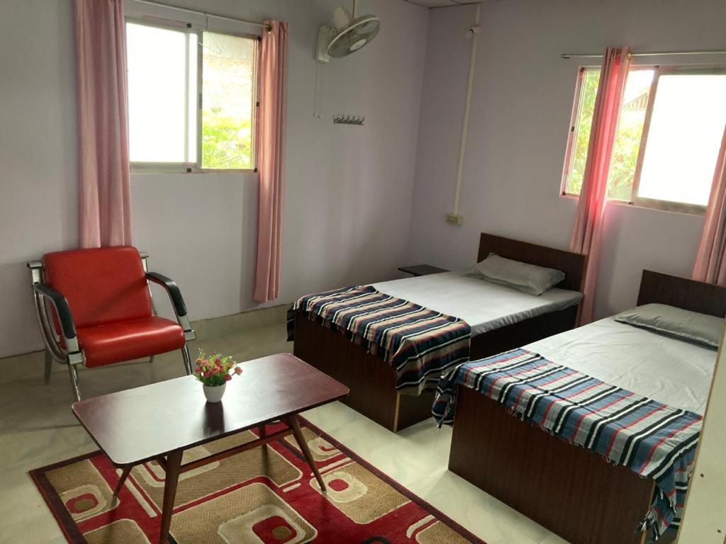 a room with two beds and a chair and a table at Haobam House in Imphal
