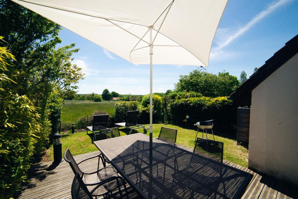 a table with a white umbrella on a deck at Cottage "Les ETANGS" à quelques pas du Lac de la forêt d'Orient - Les Cottages du Belvédère in Mesnil-Saint-Père