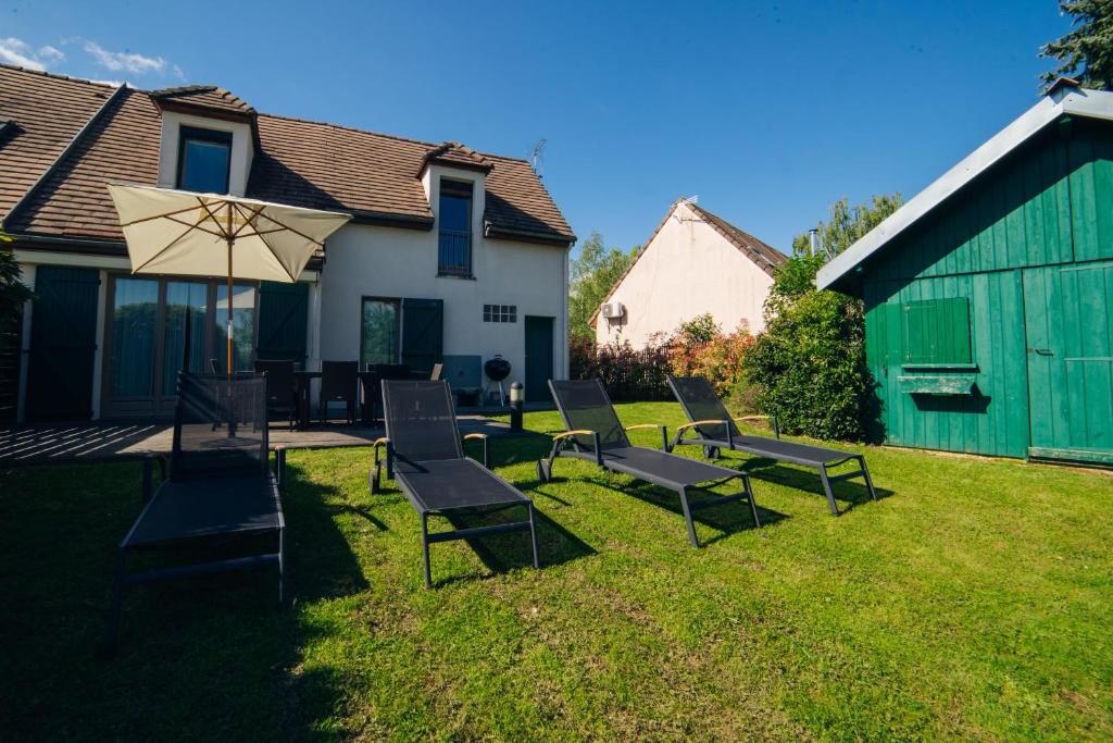 a group of chairs and an umbrella on a yard at Cottage "La CANOPEE" à quelques pas du Lac de la forêt d'Orient - Les Cottages du Belvédère in Mesnil-Saint-Père