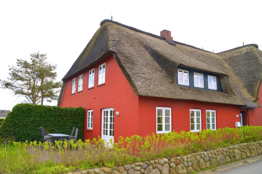 a red house with a thatched roof at Mühlenhaus 3 in Wrixum