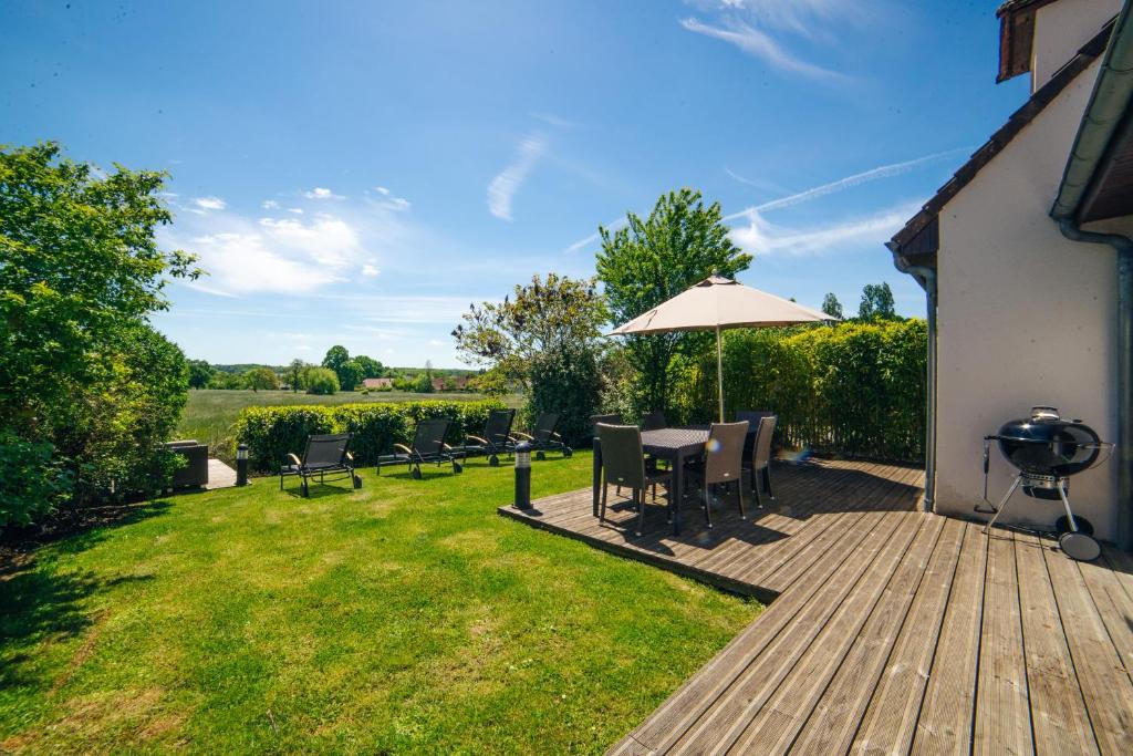a wooden deck with a table and chairs and an umbrella at Cottage "L'HERBIER" à quelques pas du Lac de la forêt d'Orient - Les Cottages du Belvédère in Mesnil-Saint-Père