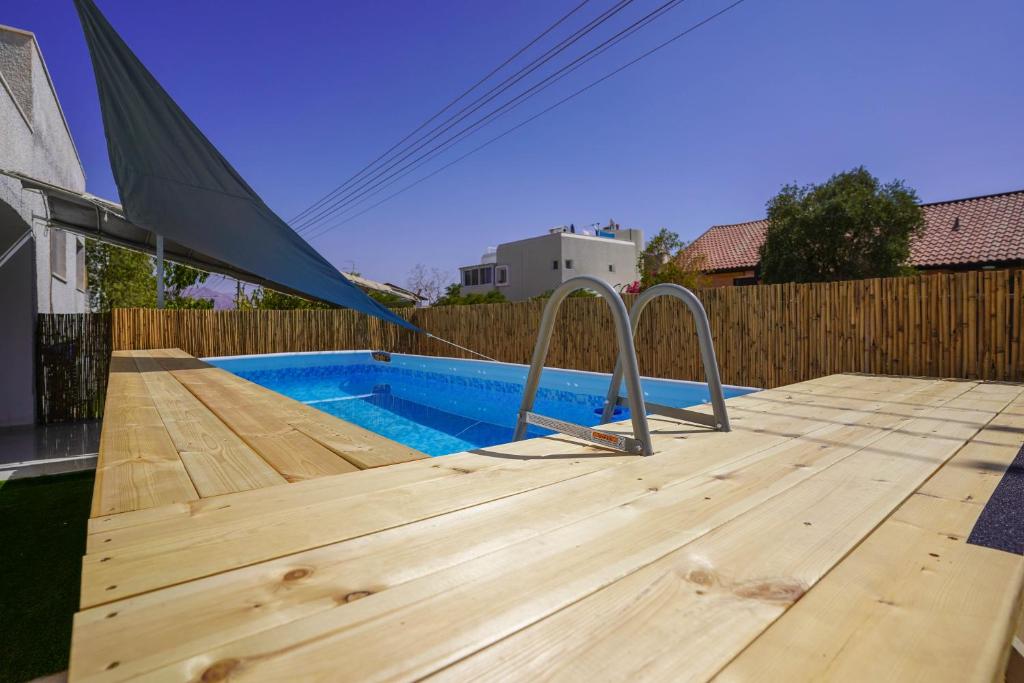 eine Holzterrasse mit einem Pool und einem Zelt darauf in der Unterkunft YalaRent Green Garden Villa with Private Pool in Eilat