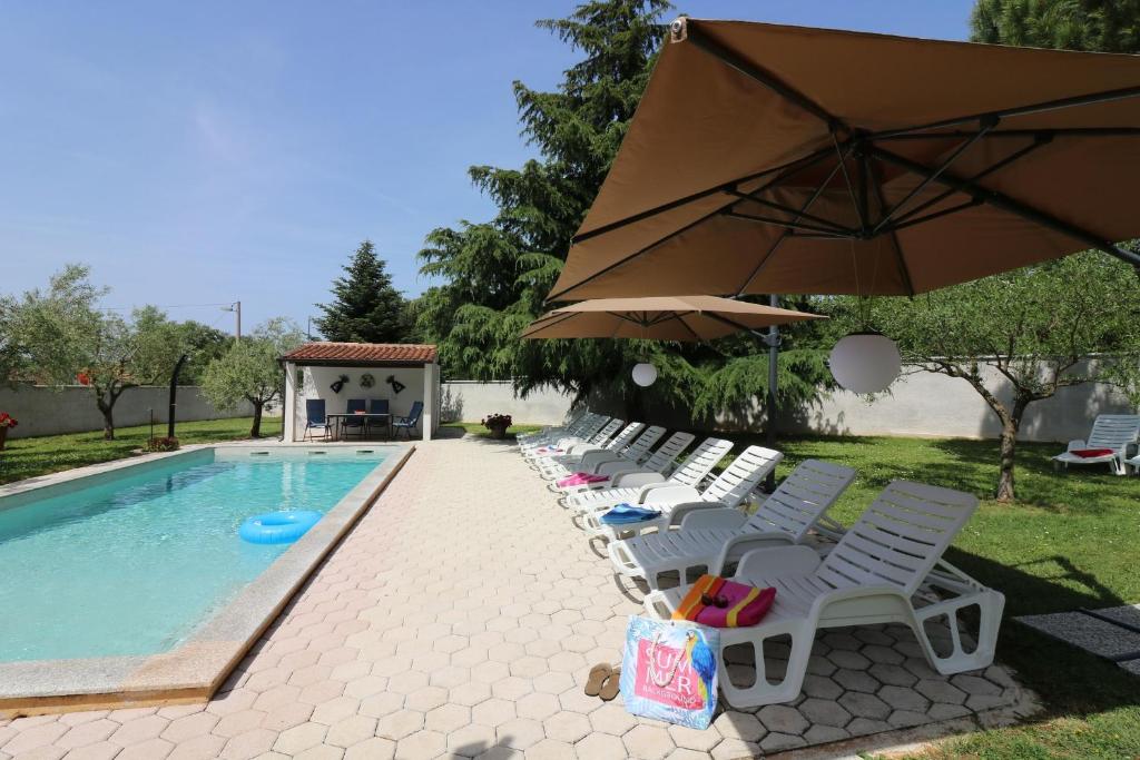 un gruppo di sedie e un ombrellone accanto alla piscina di Residence Lorena Bungalow Lavanda 1 a Poreč (Parenzo)