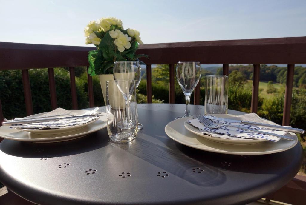 una mesa con platos y vasos en el balcón en Ruhige Ferienwohnung mit Fernblick en Modautal