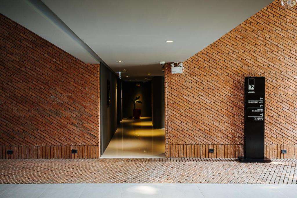A warm brick-lined corridor leads toward a dimly lit interior, with a directional sign at the entrance.