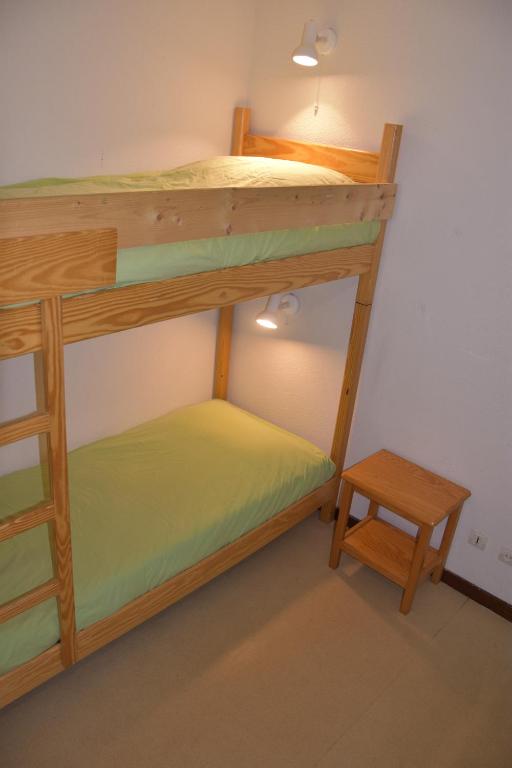 a bunk bed with a ladder and a stool in a room at La résidence du Pleynet aux 7 Laux in La Ferrière