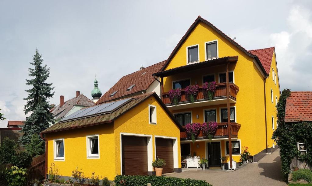 ein gelbes Haus mit Blumen auf den Balkonen in der Unterkunft Ferienwohnung-Kappl in Tännesberg