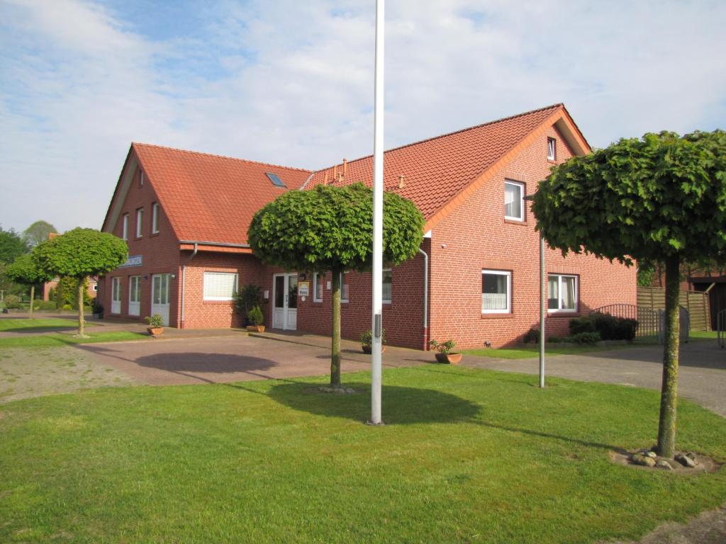 une maison en briques rouges avec un poteau dans l'herbe dans l'établissement Ferienwohnung Mauer, Wohnung "A", à Heede