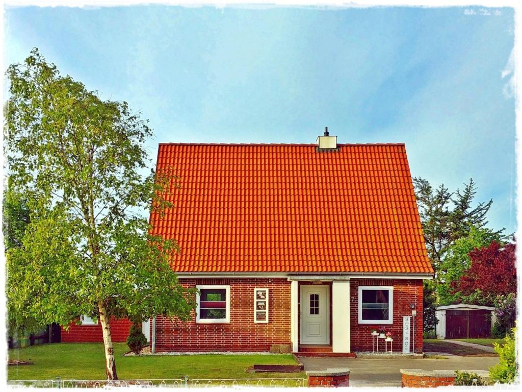 a red house with an orange roof at Hüs bi Söl - Haus bei Sylt in Uphusum