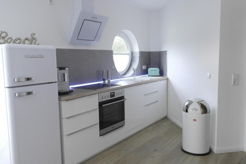 uma cozinha com um frigorífico branco e um lavatório em Ferienwohnung "Wolkenstein" - Villa Grüntal em Grömitz