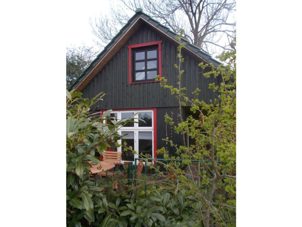 a black cottage with red trim and a red window at kleine Herta in Prerow