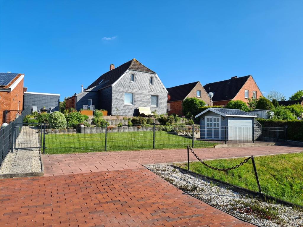 a house with a fence and a yard with houses at Schiefer Huus in Krummhörn